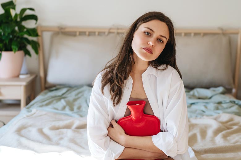 Woman with hot water bottle menstrual pain